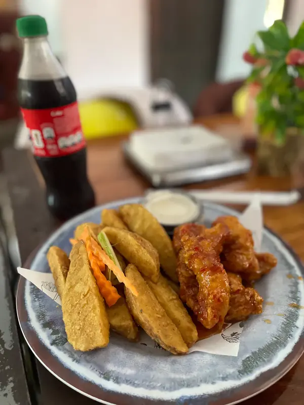 Boneless con papas gajo y una Coca-Cola en una mesa del local